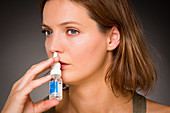 Woman using nasal spray for controlling rhinitis