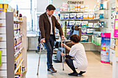 Man trying crutches in a pharmacy