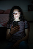 Teenage girl using a smartphone at night