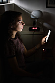 Teenage girl using a smartphone at night