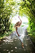 Young woman dancing on country lane