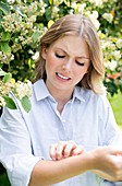 Woman by tree scratching arm