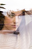 Woman looking away, view through reflective glass