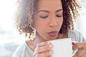 Mid adult woman blowing on coffee