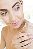 Woman rubbing body scrub on shoulder