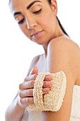 Woman using loofah mitt on arm