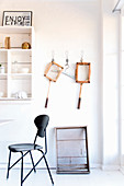 Black classic chair in front of white shelves and vintage utensils on wall
