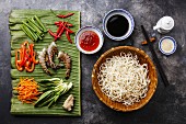Udon-Nudeln mit Garnelen und Gemüse: Zutaten auf Bananenblatt und in Schüsseln