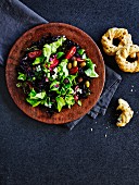 Mediterraner Blattsalat mit Tomaten und Oliven serviert mit Brot