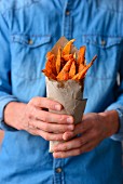 Man holds in his hands the fries of the sweet potato