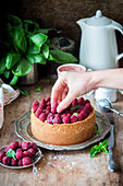 A hand decorated raspberry cheesecake with fresh raspberries