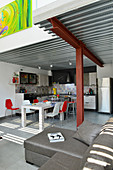 Wohnbereich mit grauer Couch und Küche und Essbereich mit Designerstühlen im Industrie-Loft