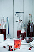 Saft (Sirup) von Kornelkirschen in Glas und Flaschen auf Küchentisch