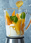 Ingredients for orange and mango dessert with honey in a mixer