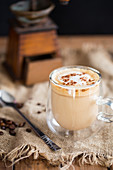 Caffe Latte im Glas vor alter Kaffeemühle