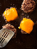 Cheeseburgers being fried in a pan