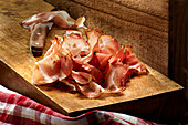 Sliced ham on a wooden board with a knife