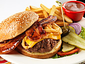 Cheeseburger mit Bacon, Pommes Frites und Barbecuesauce