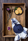 Green tea in a pot and cup, edible flowers, herbs and biscuits in a wooden box