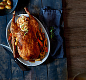 Stuffed goose with vegetables and potatoes on a wooden table