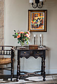 Vase of roses, wooden box and candles on antique console table with carved ornamentation