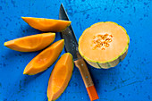 Half a cantaloupe melon and melon wedges with a knife