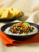 Karibischer Bohneneintopf auf Reis (vegan), im Hintergrund Maisbrot