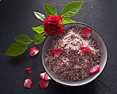 Rose petal salt with fresh petals in a ceramic bowl with a rose