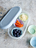 Cheese, carrot sticks and blueberries in silicone cases in a lunchbox