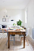 Alter Holztisch mit Stühlen im Wohnzimmer mit weißen Wänden und Holzdielenboden