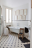 Vintage-style bathroom with gallery of pictures on wall and black-and-white patterned floor