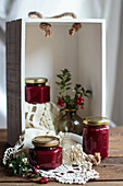 Three glasses of cranberry jam in a white wooden box