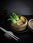 Steamed dumplings with pak choi in a bamboo steamer (Asia)