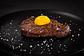 Steak mit Eigelb und Salz auf schwarzem Teller