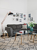 Grey corner sofa, standard lamp and coffee table with glass top on rug in living room