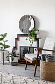 Houseplant and armchair in front of fireplace and mirror