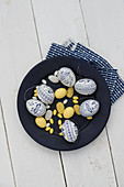 Easter eggs painted blue and white, yellow sugar eggs and marzipan eggs on plate