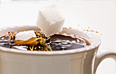 Zuckerwürfel fällt in Kaffee