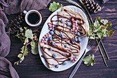 Crepes with chocolate drizzle and frozen berries and cup of black coffee