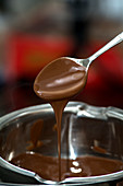 Melted chocolate dripping from a spoon into a bowl