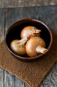 Three onions in a brown bowl
