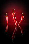 Three chilli peppers against a black and red background