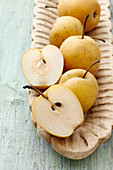 Nashi pears, whole and halved, in a long wooden bowl