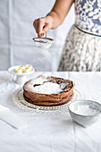 Schokoladen-Haselnuss-Kuchen mit Puderzucker bestäuben