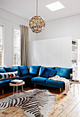 Blue seating and zebra fur in a bright living room with wooden floorboards