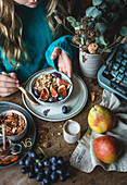 Mädchen isst Porridge mit Feigen, Nüssen, Birnen, Trauben und Mandeldrink