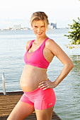 Schwangere Frau in rosa Bustier und Shorty am Steg