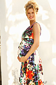 A pregnant woman wearing a floral-patterned, sleeveless summer dress