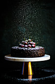 Vegan fruit cake decorated with cherries on a cake stand