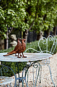 Rostige Fasanen-Figuren auf einem Metalltisch im Garten